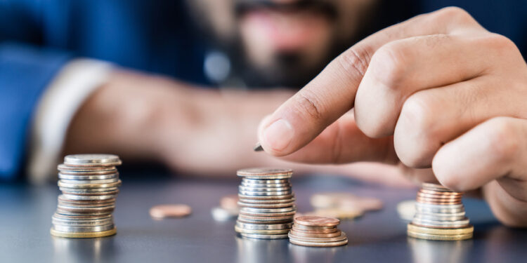 Businessman holding coins euro dollar cents counting money bills, making savings, accounting and managing currency for nest egg, mortgage loan , investments and dividends. Finance and economy concept