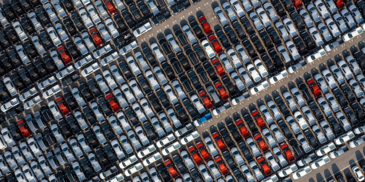 Aerial top view rows of new cars parked in distribution center on car factory, Automobile and automotive car parking lot for commercial business industry to dealership for sale.