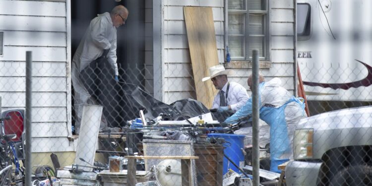 Law enforcement authorities removing bodies from a scene where five people were shot the night before Saturday, April 29, 2023, in Cleveland, TX. Authorities say an 8-year-old child was among five people killed in a shooting at the home in southeast Texas late Friday night. (Yi-Chin Lee/Houston Chronicle via AP)